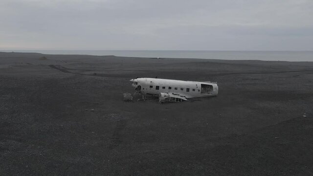 Black crows over airplane relict Douglas Dakota DC3 or C-117 on south coast of Iceland. Aerial orbit