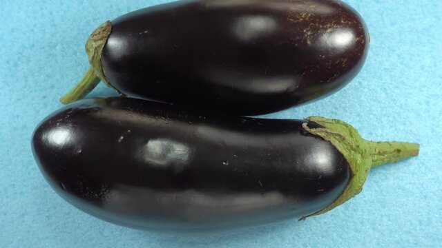 Two whole ripe eggplant vegetables rotate in 4K