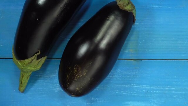 Two whole ripe eggplant vegetables on blue