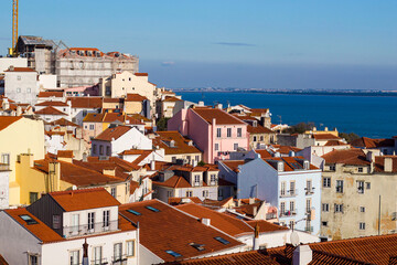 View of white houses with brown roof tiles against the sea in Lisbon, Portugal alfama district