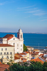 Fototapeta premium View of white houses with brown roof tiles against the sea in Lisbon, Portugal alfama district