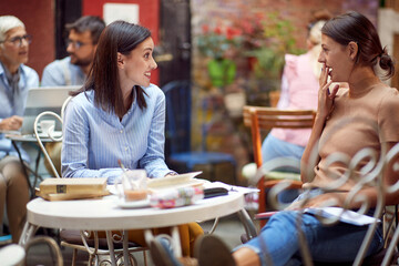Two female students gossiping while have a drink in bar's garden. Leisure, bar, friendship, outdoor