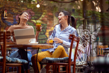 Two female friends have a good time while having a drink at the bar. Leisure, bar, friendship, outdoor