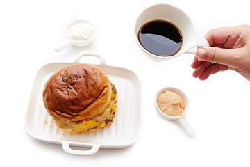 Cheeseburger in white dish, Hand holding a mug of coffee, isolated on white background.