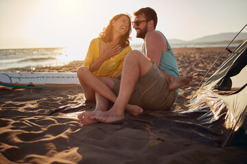 Young couple of surfers is having a good time while camping at the beach at sea together. Summer, vacation, sea, relationship