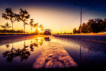 Sunset after rain, the car on the highway. Wide angle view of the dividing line level in a puddle
