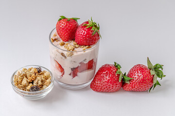 homemade delicious layered dessert of yogurt, muesli and strawberries on a white surface