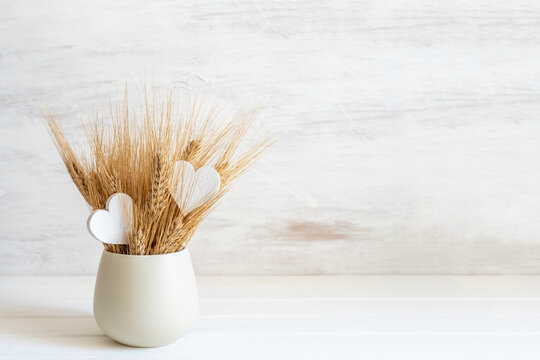Bouquet of wheat ears on white wooden background with copy space.