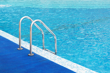 Metal railing in the pool for safety when descending into the water.Handrails for people in the public pool.