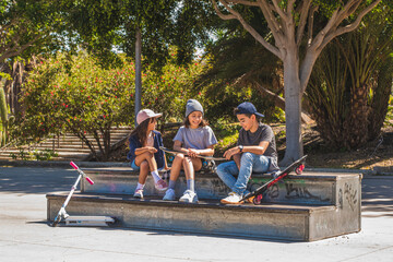 Three skating kids, sitting in a skate park talking and laughing together.