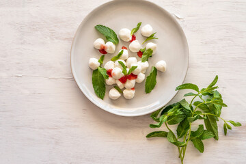 Mozarella balls with strawberry jam and mint bunch over white background.