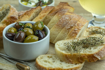 Rustic bread and pickled olives over wooden background. Mediterranean snacks.