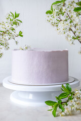 Wedding pink cake cake on a stand among branches of cherry blossoms