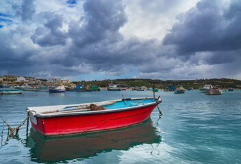Fototapeta na wymiar The old fishing boat is moored at the coast of Marsaxlokk village