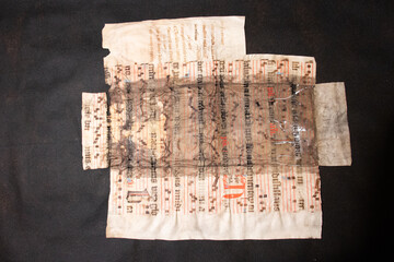 A medieval manuscript hand written onto parchment or vellum and illuminated with red initial flourishes in pen. Many manuscripts were used in the C15th and C16th as binder's waste for bookbinding.