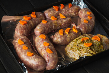 Raw meat sausage with carrots and ham on a Sheet pan is prepared for baking in the oven. The national meat dish is prepared before the holidays
