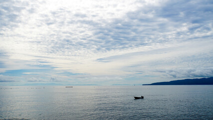 大海原と釣り船と雲がかった空
