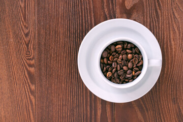 white cup, saucer and coffee beans on a wooden background