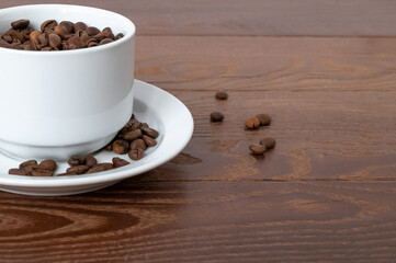white cup, saucer and coffee beans on a wooden background