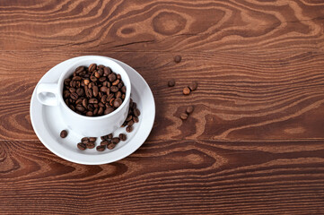 white cup, saucer and coffee beans on a wooden background
