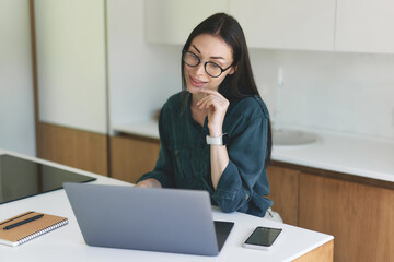 Front view of business woman working from home with laptop, smartphone and notebook