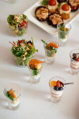festive appetizer in a glass cup with shrimps and arugula and dessert with berries and culinary cream