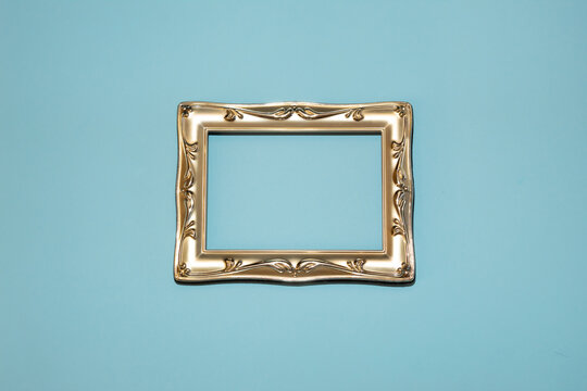 Golden Color Frame On Pastel Blue Background. A Perfect Imitation Of Real Gold. Flat Lay.
