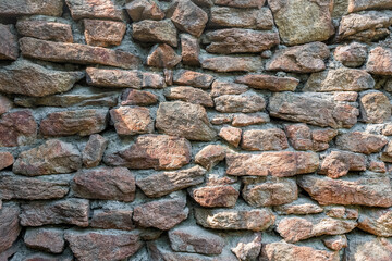 The stone wall is made of red granite blocks.The texture of natural stone.