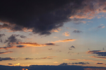 Dramatic dark clouds illuminated by evening sun on the sky.