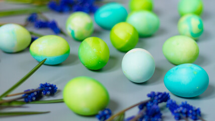 Fototapeta na wymiar Easter background of green and blue eggs in harmony with the natural shades of flowers