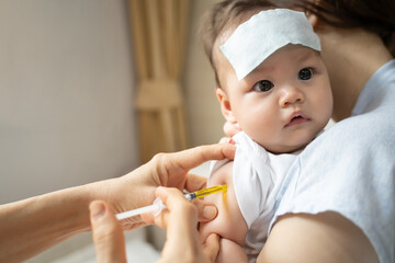 asian baby infant get fever and apply cool patch on forehead getting injection for vaccination on...