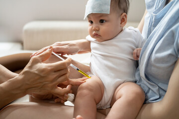 asian baby infant get fever and apply cool patch on forehead getting injection for vaccination on...
