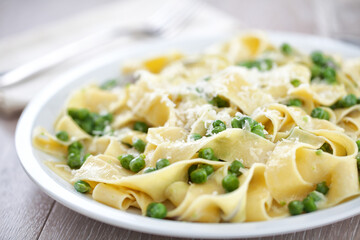 Tagliatelle pasta with cream and peas on a plate.