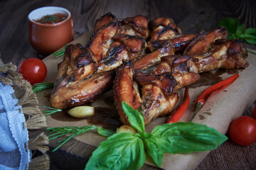 Delicious fried chicken wings lie on the serving board, decorated with various spices , herbs and vegetables.