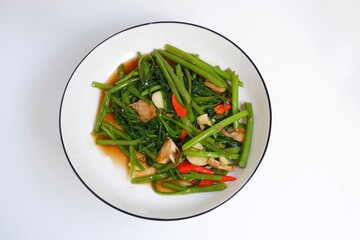 Stir fried morning glory on a white plate on white background