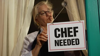 Female shop owner putting Chef Needed sign on glass door. Woman staff chef of restaurant advertising for hiring staff.
