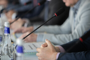 Businessman giving interview at table with microphones, closeup. Journalist conference