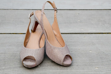 Pair of summer shoes with high heels on wooden surface. Horizontal view of footwear.