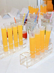 Orange drink in test tubes with focus on the first tube from the front. Vertical view.