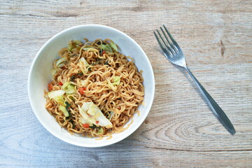 spicy fried instant noodles with cabbage and basil leaf on bowl