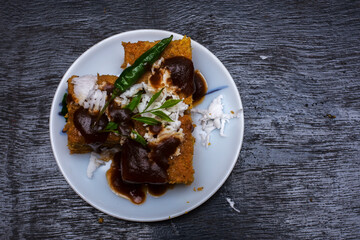Gujarati khaman Dhokla made with chana dal served with coconut and chutni on a white plate and black background.