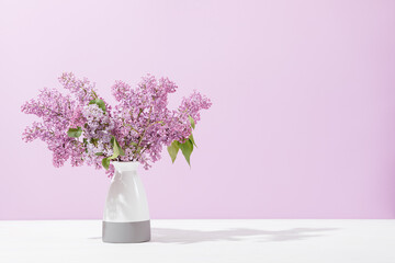 Fresh lilac bouquet in vase on white table