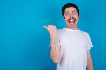 young handsome Caucasian man with moustache wearing white t-shirt against white background showing thumb up down sign