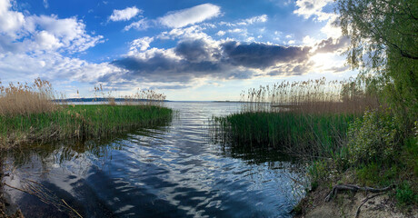 sunset over a large pond. Beautiful nature. Calm water in the river. Silhouettes of trees on the horizon. The last rays of the sun are reflected in the water. Light clouds in the sky. European nature.