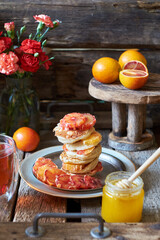 Pancakes with red oranges on a wooden background. Side view.