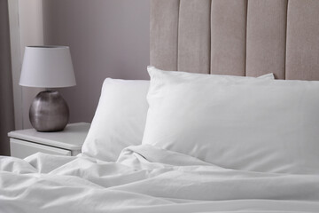 White soft pillows on bed and lamp in room