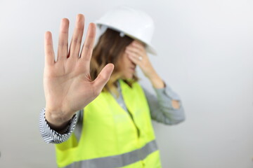 Female architect or engineer wearing hardhat and reflecting jacket in shock covering face and eyes...