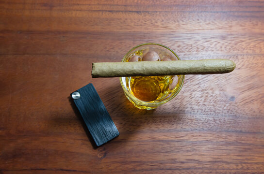 Cigar on a wooden table and whiskey  Soft focus image.