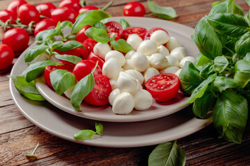 Caprese salad with tomato, mini mozzarella and basil on a old wooden table.