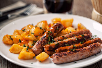 Sausages and roasted potatoes on a plate. High quality photo.